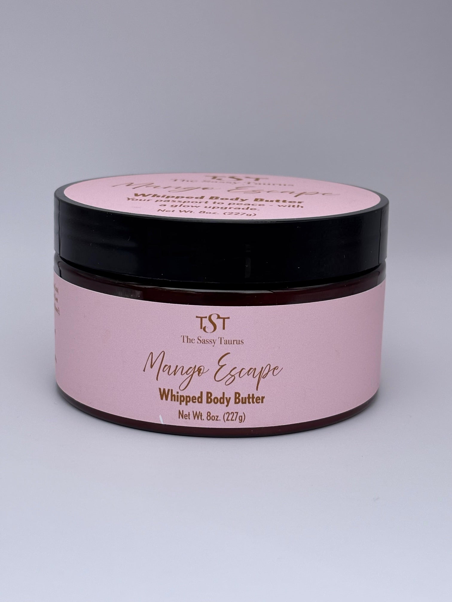 Pink jar of TST Mango Escape Whipped Body Butter on a gray background